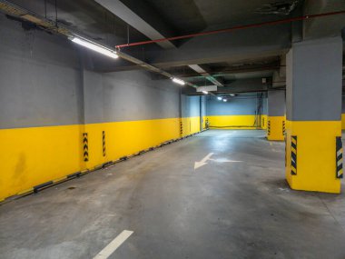 Geniş ve iyi aydınlatılmış bir yeraltı otoparkı modern bir his için parlak sarı ve gri duvarlara sahiptir.