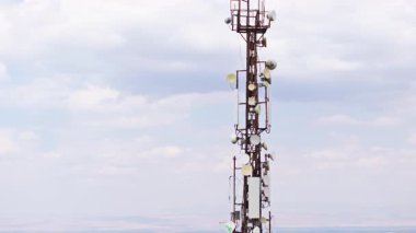 Bulutlu gökyüzünün önündeki telekomünikasyon kulesi, insansız hava aracının yörüngesinde.