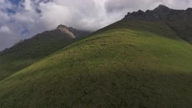 Kırgızistan 'da güneşli yaz gününde muhteşem yeşil dağ yamaçları. Tian-Shan dağlarının tepesindeki mavi gökyüzü, insansız hava aracı bakış açısı.