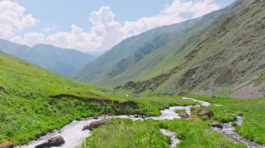 Kırgızistan 'da güneşli yaz gününde yeşil yamaçlı pitoresk dağ geçidi. Tian-Shan dağ sırasının üzerinde beyaz bulutlu mavi gökyüzü, Dolly ileri kamera hareketli drone bakış açısı.