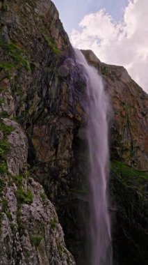 Kırgızistan 'da güneşli bir günde uçurumun gölgesinde Belogorka şelalesi