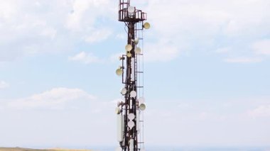 Gökyüzünün ve ufuktaki dağların önündeki telekomünikasyon kulesi.