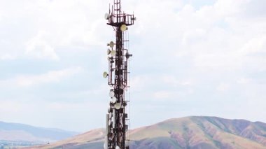 Gökyüzünün ve ufuktaki dağların önündeki telekomünikasyon kulesi.