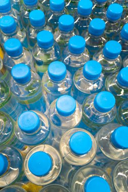 Mavi kapaklı plastik su şişeleri, tam kare yakın çekim.
