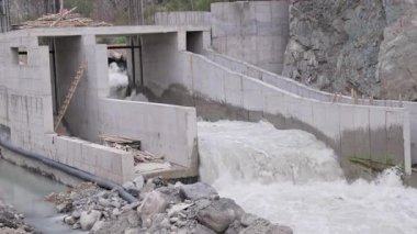 Bir dağ nehrinin üzerine kısmen küçük bir hidroelektrik santrali inşa edildi. Somut kanallar su akışını yapıdan yönlendirir. İnşaat malzemeleri ve bir merdiven görülebilir. 120 fp 'den ağır çekimde vuruldu..