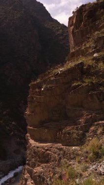 Güneşli yaz gününde, kanyonun dibinde dağ nehri olan tortulu kayaların tepesine çıktım.