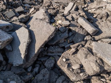 Güneşli bir günde kaldırılan asfalt moloz yığını, tadilat sırasında yoldan kaldırılan büyük enkaz parçaları.