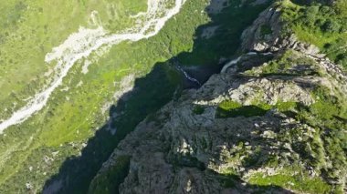 Kırgızistan 'da güneşli bir yaz gününde arka planda Belogorka şelalesi ve dağ zirvesi, doğrudan insansız hava aracı manzarasının üstünde.