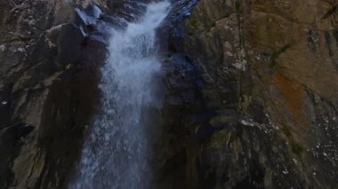 Dağlardaki dağ vadisinde küçük bir şelale güneşli yaz kırgızistan 'da kapalı hava aracı manzarası. Açık hava ve engebeli arazi. Dolly geri kamera hareketi,