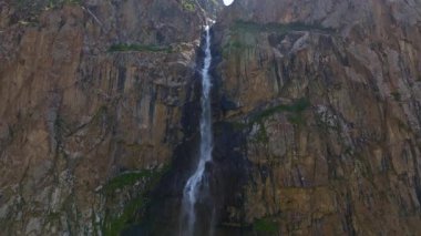 Dağlardaki dağ vadisinde küçük bir şelale güneşli yaz kırgızistan 'da tam kare hava aracı manzarası. Açık hava ve engebeli arazi. Kamera hareketini arttır.