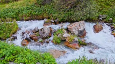 bulutlu yaz gününde kayaların arasından akan beyaz su, yüksek açı manzarası