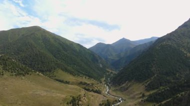 İnsansız hava aracı patlaması, Zhylamysh 'in üzerine yatay bir eksen ile iner, kıvrımlı bir nehir, yeşil yamaçlar ve parçalı bulutlu bir gökyüzünün altında zirveleri olan bir dağ vadisini yakalar..