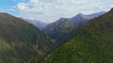 drone view approaching to steep green mountain cliff edge at summer day in Kyrgyzstan