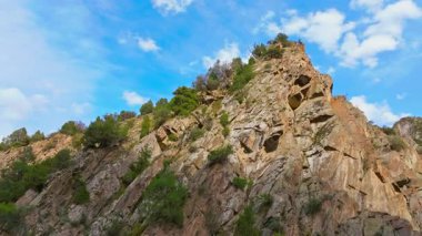 Drone görüntüleri, Kırgızistan 'daki bir dağ vadisinde kayalık bir kayalık kayalık kayayı yakalar. Dokusunu ve derinliğini, sola doğru pürüzsüz bir yay hareketiyle gözler önüne serer. Uzaktan kumlu, el değmemiş manzarayı gösterir..