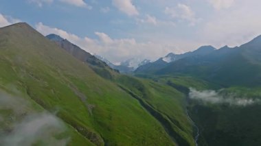 Kırgızistan, Chunkurchak geçidinde yaz mevsiminde beyaz bulutlu yeşil dağların insansız hava aracı görüntüsü. Dolly ileri kamera hareketi.