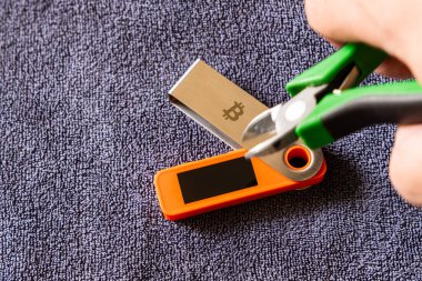 hardware Bitcoin wallet with wire cutters indoors, cold storage hacking and physical vulnerability concept