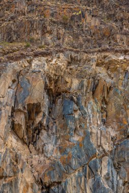 Full-frame background of rugged sedimentary rock formation in Kyrgyzstani mountains. Daylight enhances the austere mood of this natural texture.