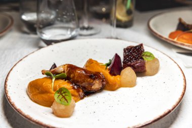 Bıldırcın bacaklı restoran masası, ezilmiş kabakla servis edilen ördek göğsü.