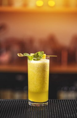 Ananas dilimi ve fesleğenle süslenmiş soğuk taze ananaslı uzun bardak.