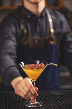 Barmen barda sarı martini servisi yapıyor.