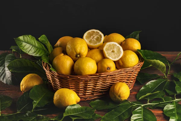 Eski Ahşap Masa Üzerinde Yaprakları Olan Bir Sepet Taze Limon — Stok fotoğraf