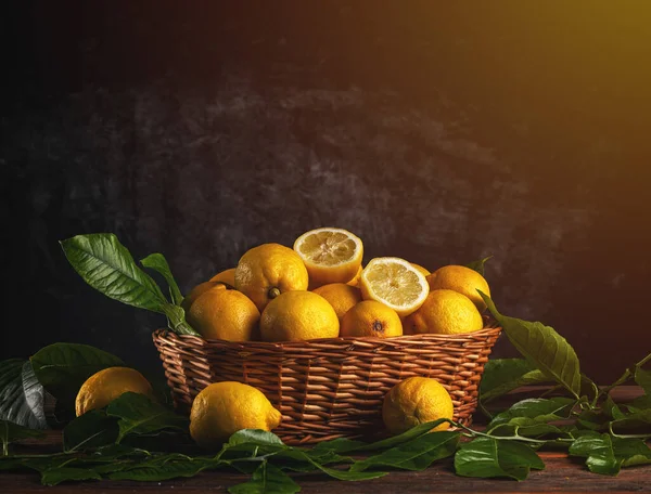 木のテーブルの上のバスケットに葉を持つ新鮮な有機レモンの果物 コピースペース — ストック写真
