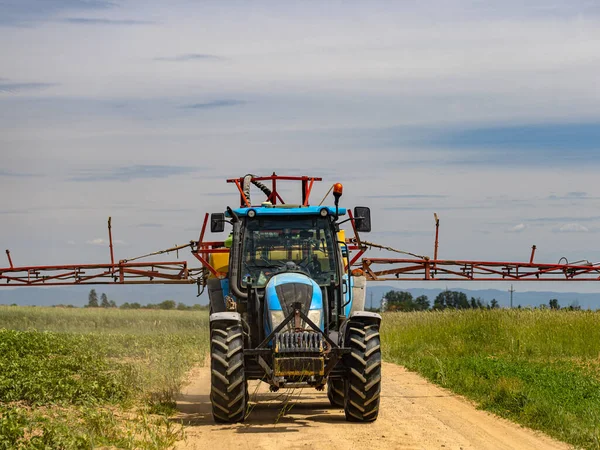 トラクターは緑のオート麦畑に植物保護製品を噴霧するために行きます — ストック写真