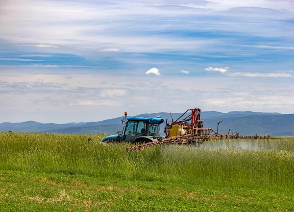 在绿色燕麦田上工作的喷洒机 — 图库照片