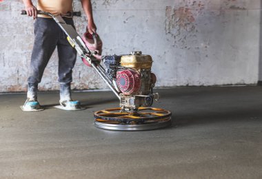 Beton yüzeyi öğüten bir odada inşaat işçisi.