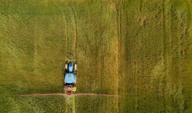 Traktör tarlada böcek ilacı kimyasallarıyla gübreleme yapıyor.