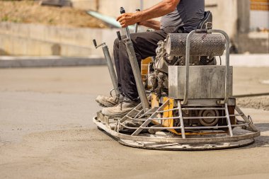 Beton zemin son sürtünmesi. İşçi özel inşaat ekipmanları makinesiyle beton döşeyip bitiriyor