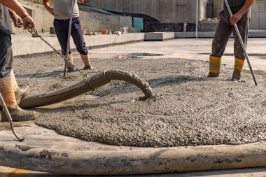 İnşaat işçisi inşaat alanında ıslak beton döküyor.