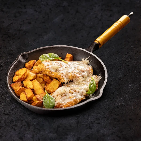 Kalfsschnitzel Met Geraspte Kaas Gegarneerd Met Gebakken Aardappelpartjes Zwarte Achtergrond — Stockfoto