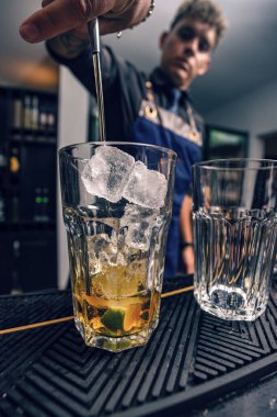 Bar tezgahında alkol kokteyli, garnitürle kokteyl yapan barmen.