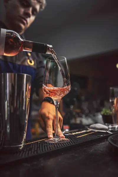 Barman at work, pouring wine in wine glass