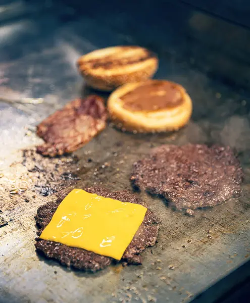 Cooking burgers on hot grill with cheese