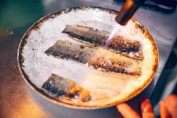 요리사는 토치를 사용하여 물고기를 요리합니다 레스토랑 로열티 프리 스톡 사진
