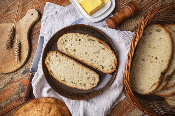 Dwa Kromki Chleba Rzemieślniczego Talerzu Obok Masła Kosza Chleba Tworząc Obrazek Stockowy