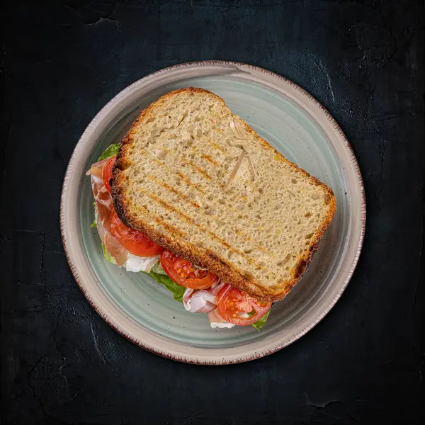 头顶上的一个美味的烤三明治 有新鲜的配料和深色背景 免版税图库图片