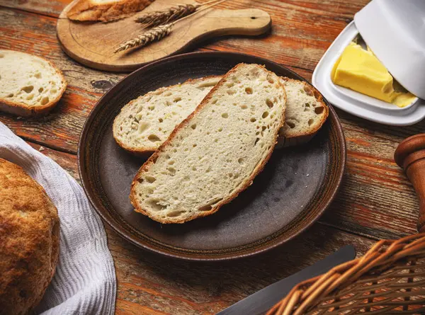 新鲜切碎的手工面包 在木制桌子上涂上黄油 四周都是生硬的厨房用品 图库图片
