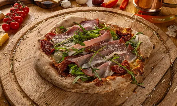 Handwerkliche Pizza Mit Sonnengetrockneten Tomaten Schinken Rucola Und Käse Serviert Stockbild