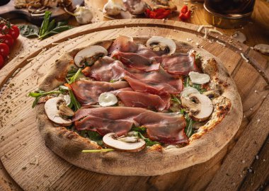 Gurme prosciutto ve tahta tahtada mantarlı pizza.