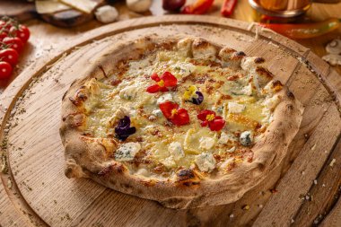 Pizza Quattro formaggi tahtadan kesme tahtasında yenilebilir çiçeklerle süslenmiş.
