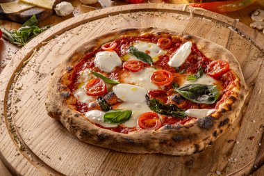 Margherita pizzası, taze fesleğen, domates ve ahşap bir masada mozzarella.