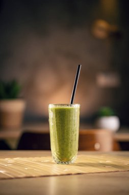 Modern mutfakta samanla bambu hasırının üzerinde duran yeşil smoothie.