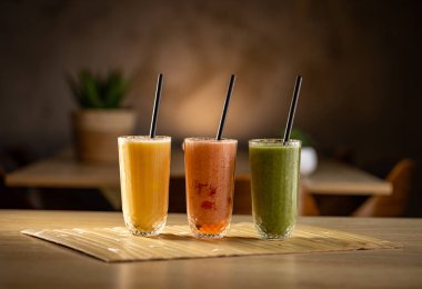 Tahta masada siyah pipetli üç farklı ferahlatıcı içecek. 