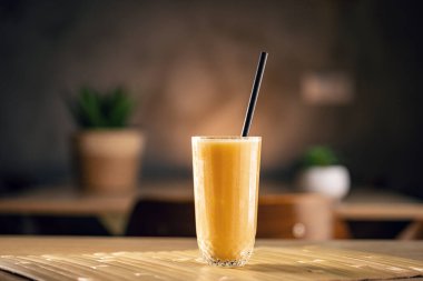 Bir kafedeki masada duran serinletici sarı smoothie.