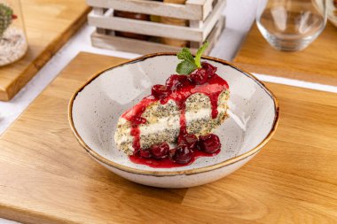 Bir dilim haşhaşlı kek ve kiraz sosu tabakta duruyor.