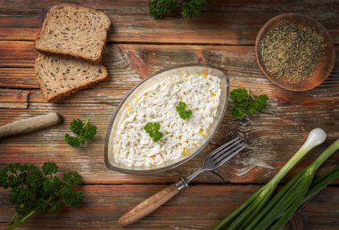 Kırsal ahşap masada, rendelenmiş peynirli bir kase dolusu polenta.
