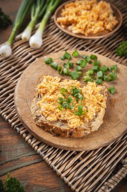 Bir dilim ekmek, ev yapımı yumurta salata ve tahtadan taze soğan.